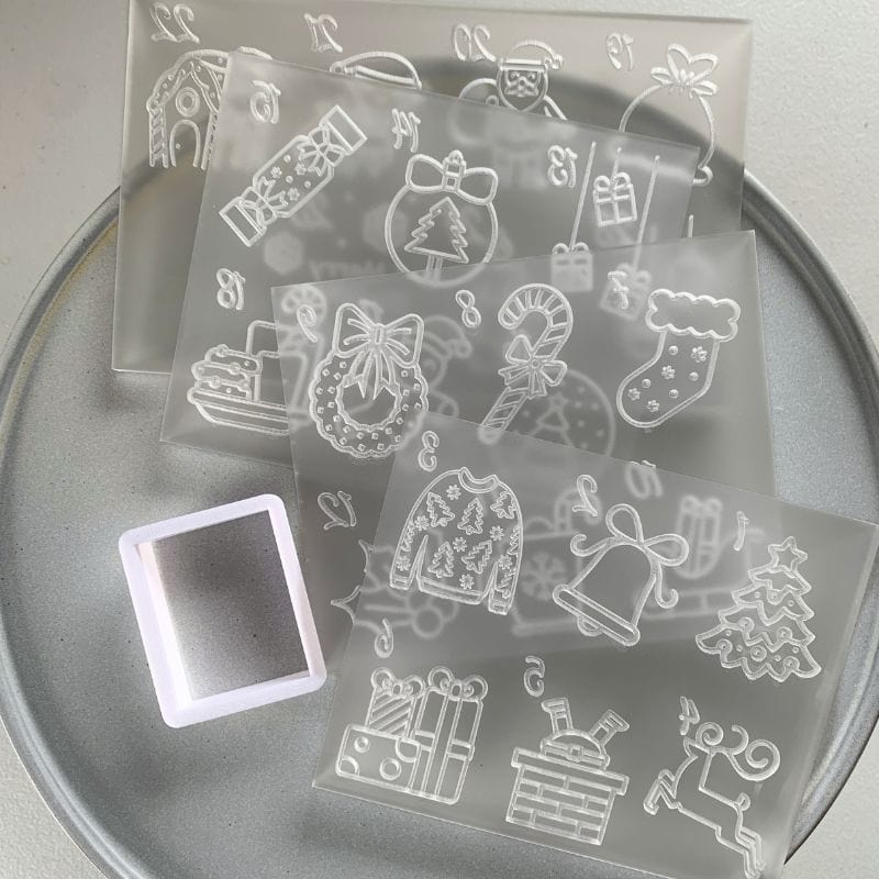 Set of acrylic Christmas advent cookie embossers with festive holiday designs and a rectangular cookie cutter.