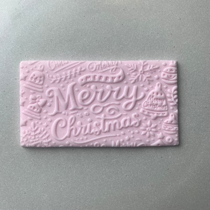 Rectangular fondant cookie embossed with Merry Christmas typography from a holiday embosser stamp