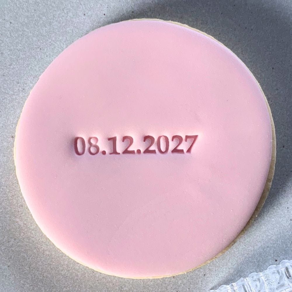 Close-up of a crisp date imprint on a fondant cookie, created with a custom stamp